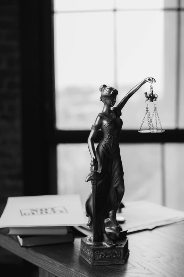 Justice statue on desk with person working
